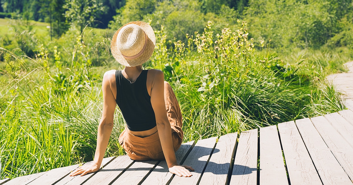 Woman sitting on deck overlooking landscape.